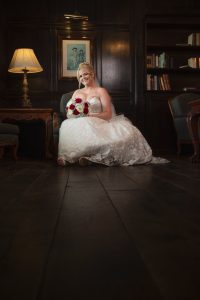 Bride seated with a red and white bouquet in a wood-panelled room at Webbington Hotel